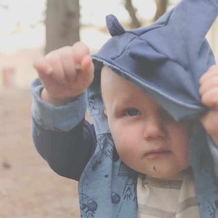Toddler wearing a custom reversible Merino wool jacket with bear ears, playing outdoors to show fit and flexibility. Jacket made by TK Clothing